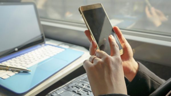 Close-up of a woman typing on a smartphone keyboard on a train