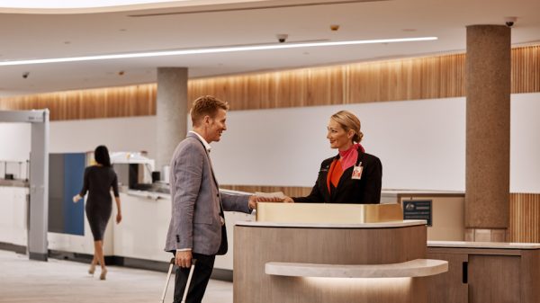 A Qantas employee welcoming a customer at an airport lounge